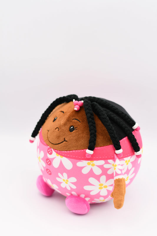 Plush toy with a child-like face and black hair styled in braids, wearing a pink outfit with floral patterns on a white background.