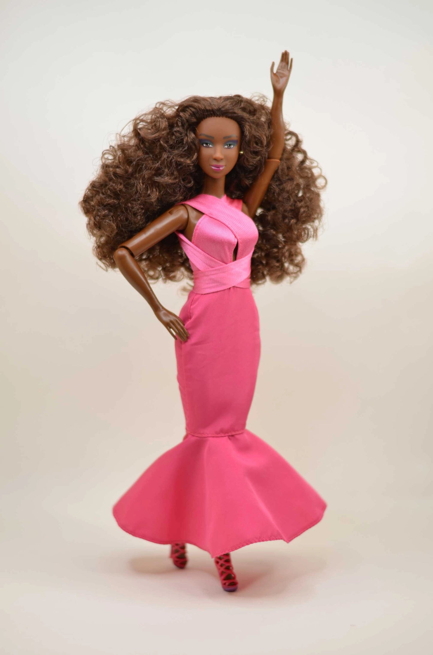 Barbie doll with long brown hair wearing a pink dress on a white background
