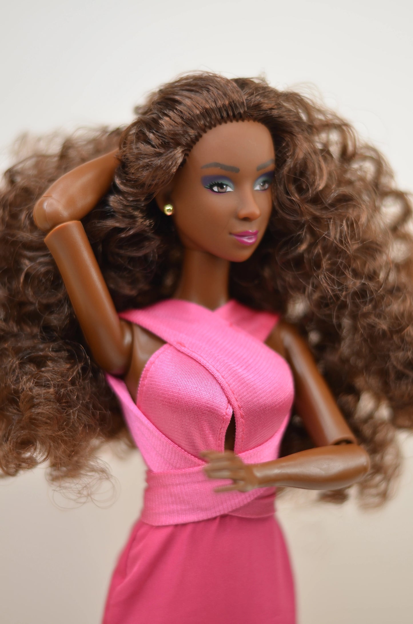 Barbie doll with long brown hair wearing a pink dress on a plain background