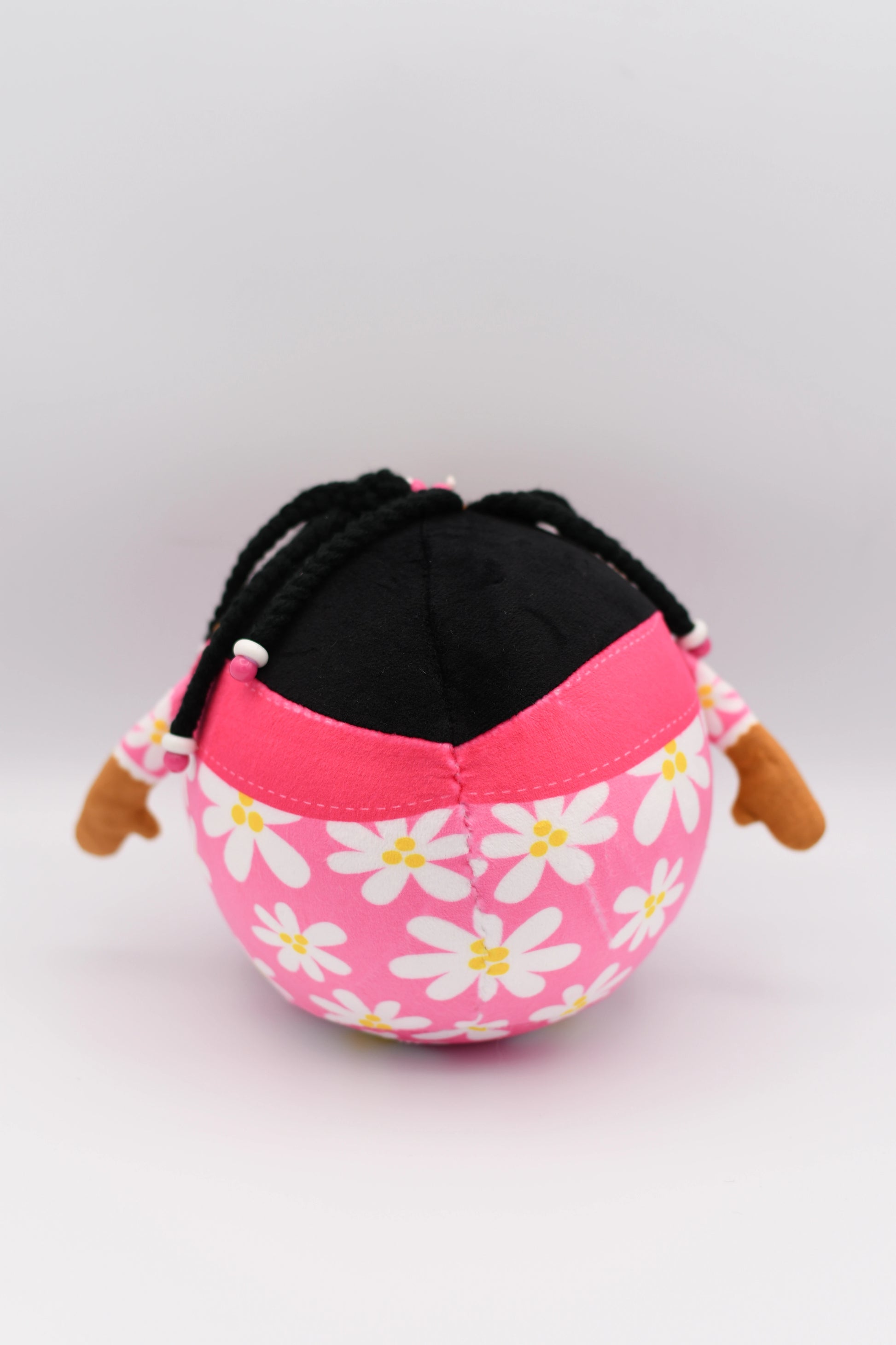 Pink fabric pouch with white floral patterns and black drawstring on a light gray background
