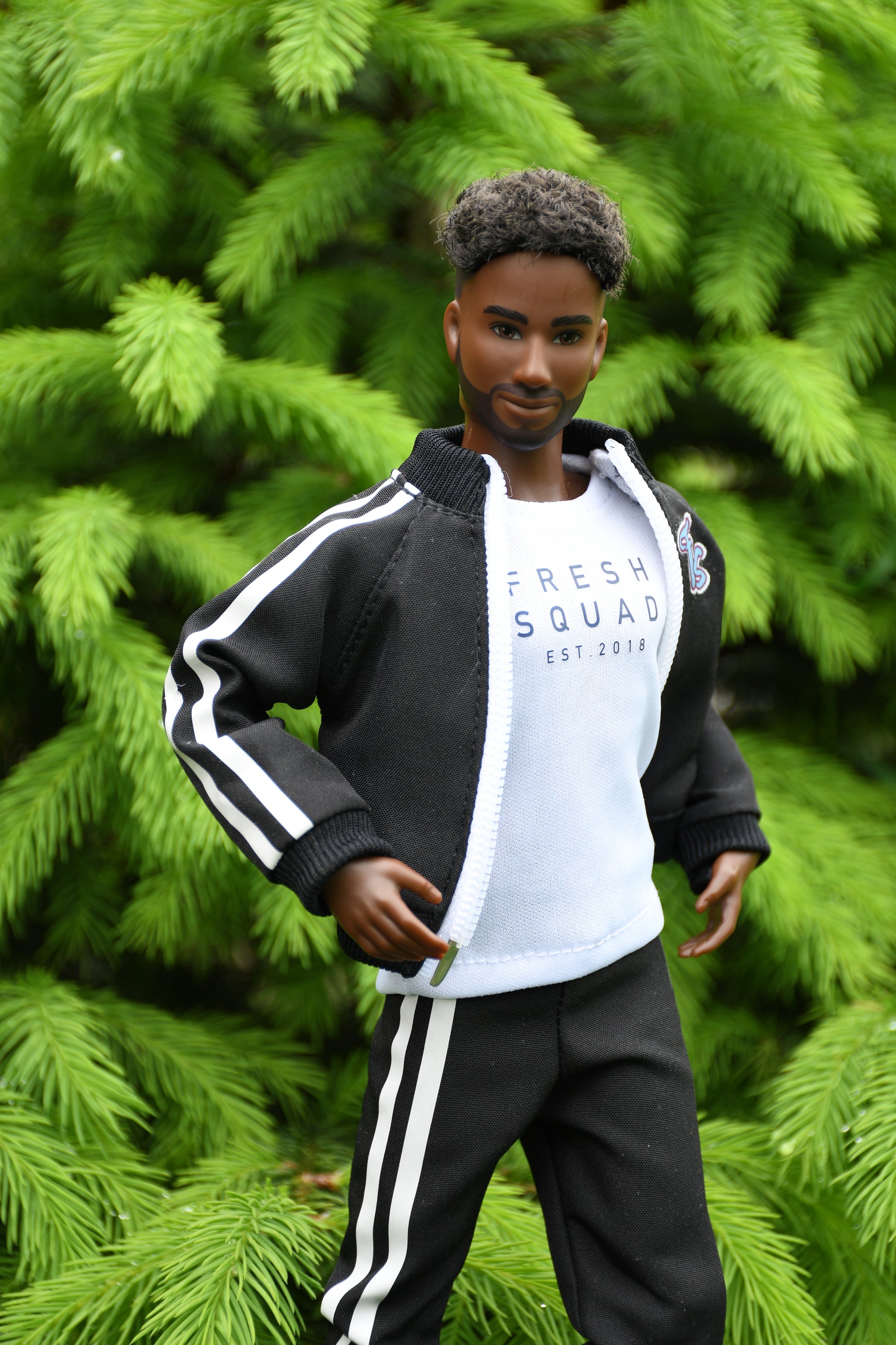 Mannequin wearing a black and white tracksuit with 'Fresh Squad' text against a green foliage background