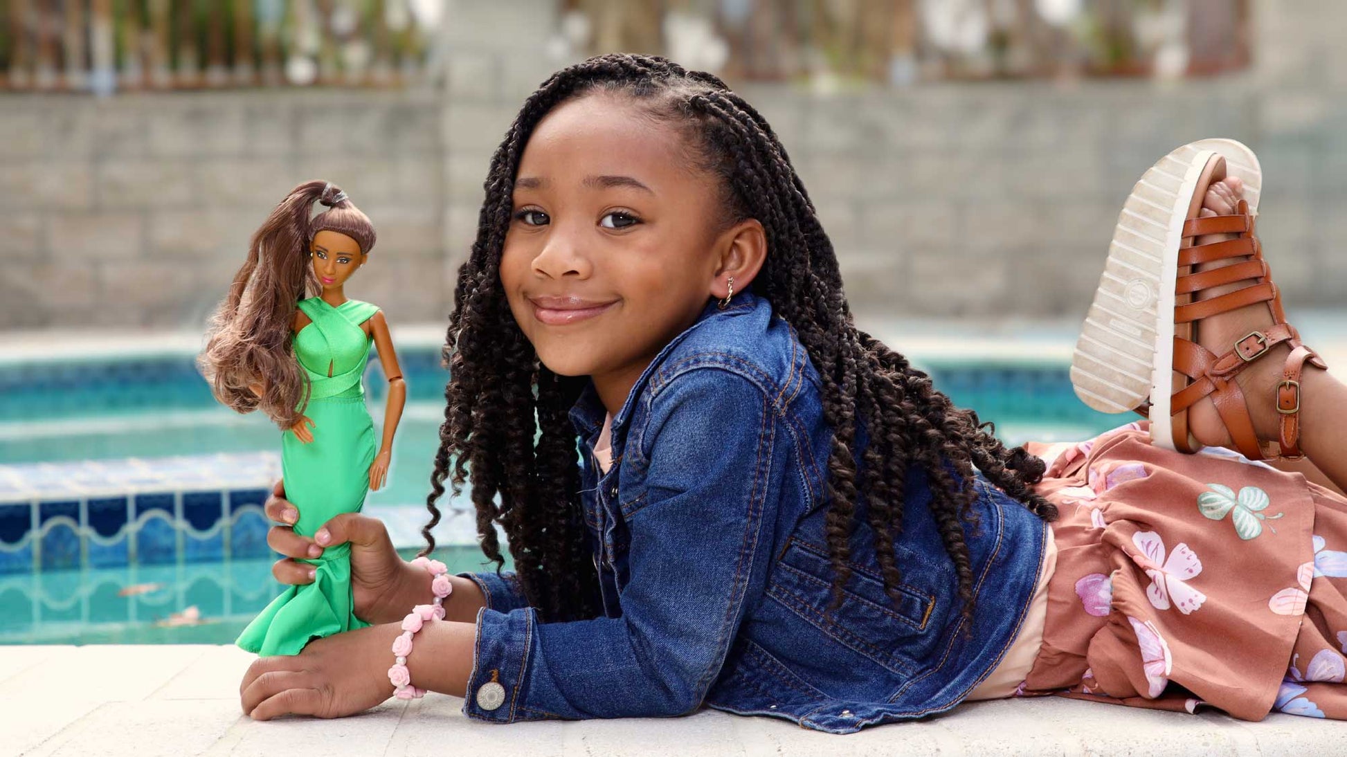 Young girl holding a doll by a poolside