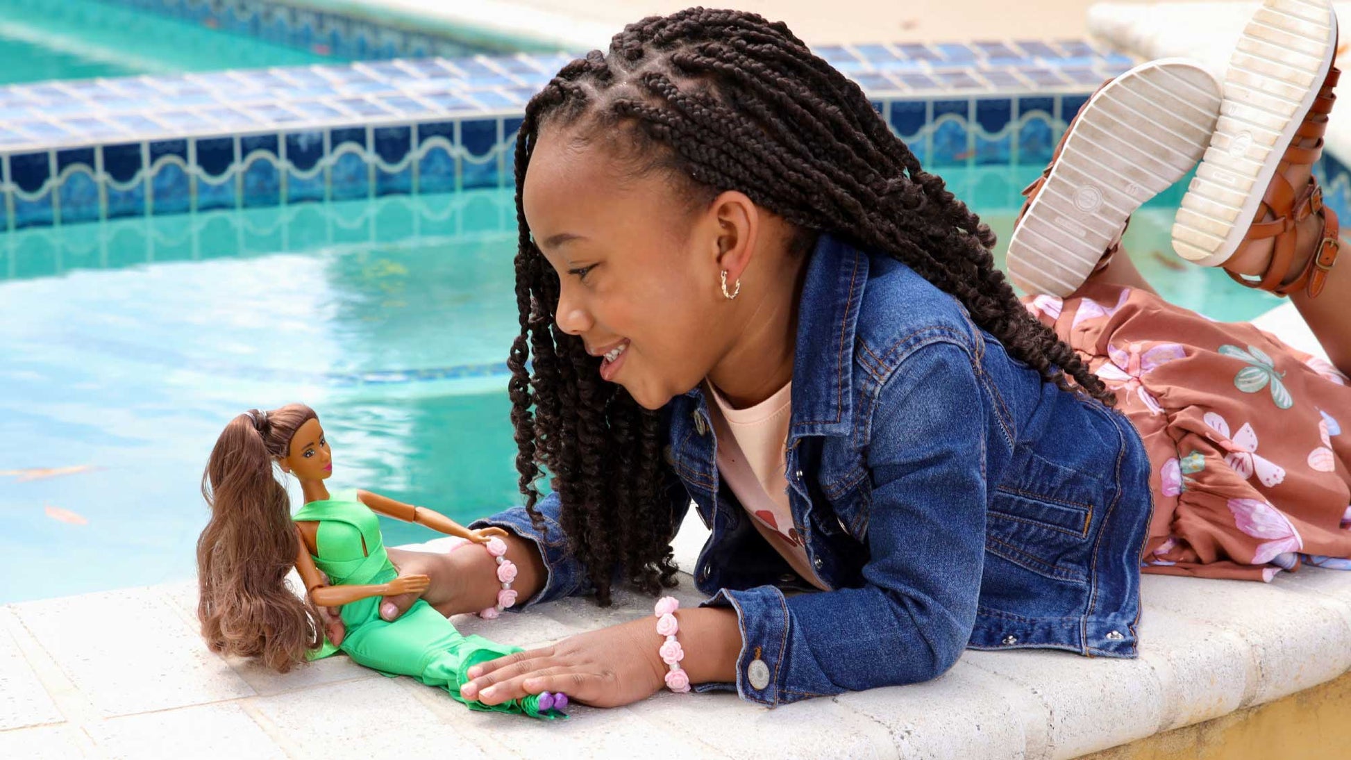 Young girl playing with dolls by a poolside