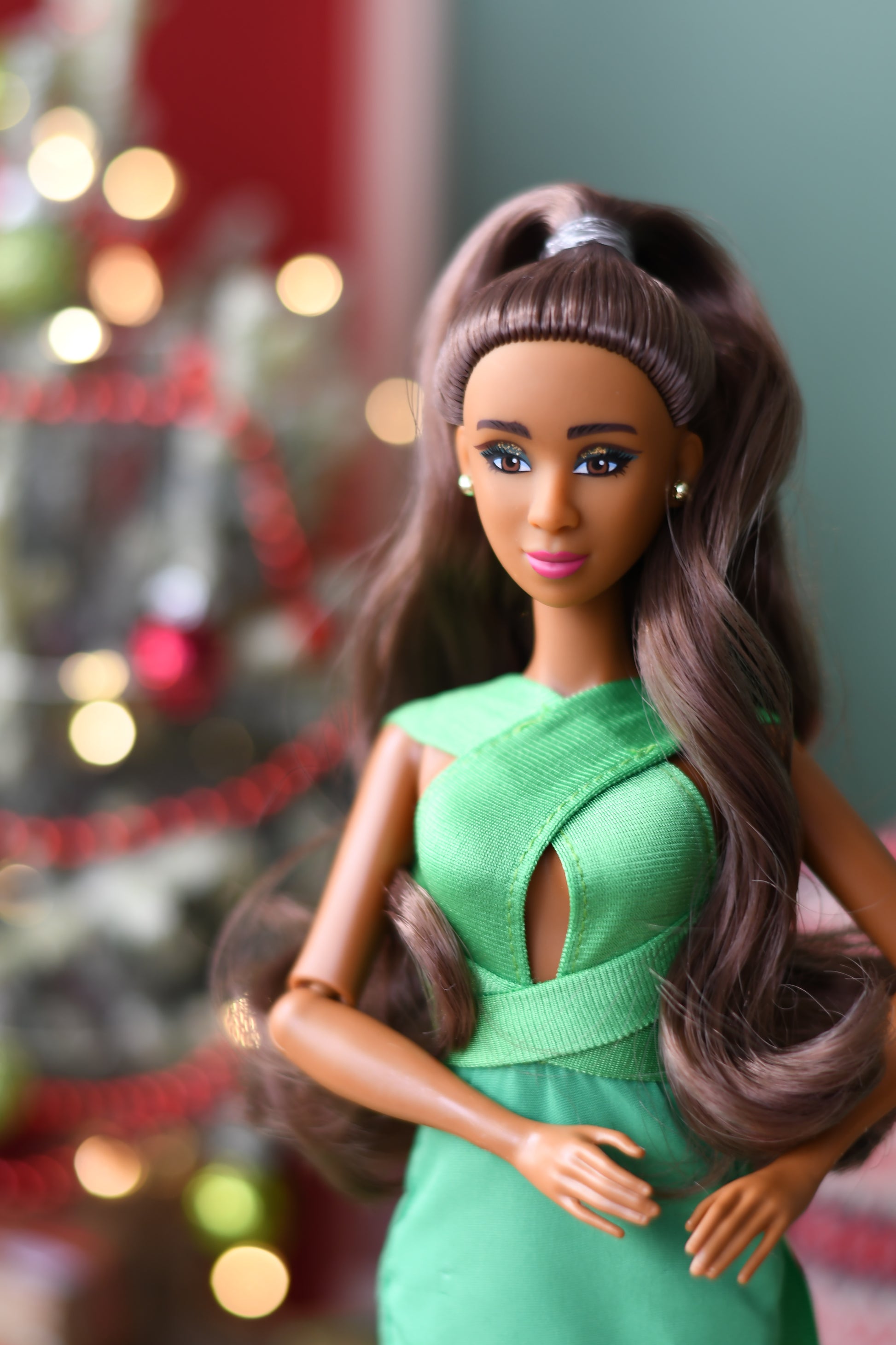 Barbie doll with green dress against a blurred festive background