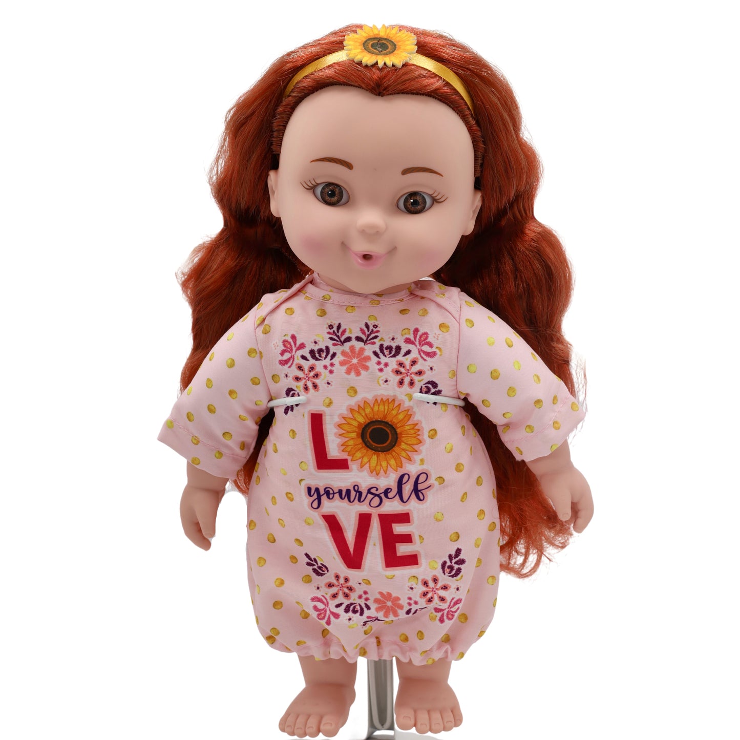 A toddler doll with red hair, wearing a pink floral dress with the text 'LOVE' and a sunflower design.