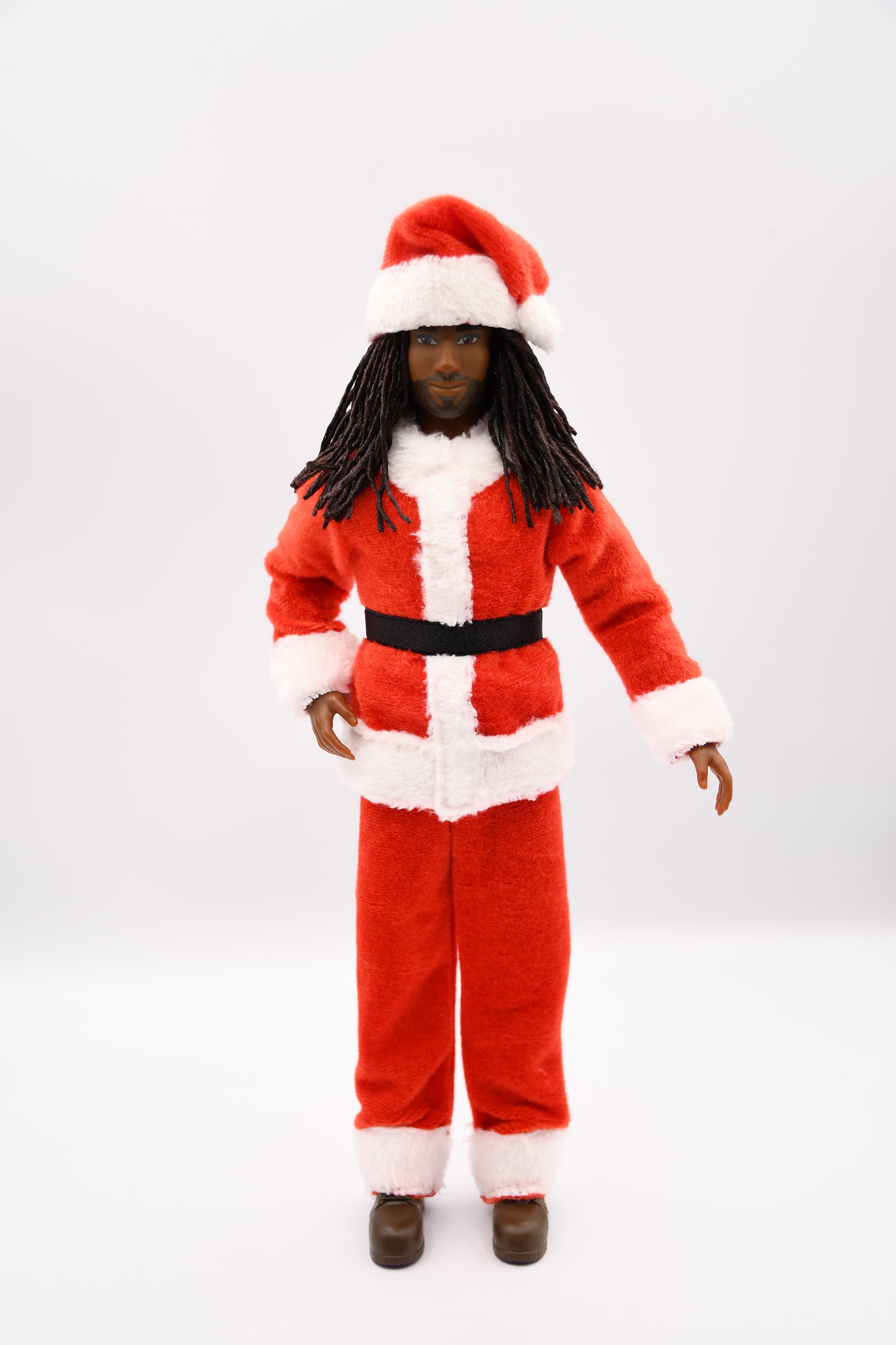 Doll wearing a red Santa outfit with a white hat on a light gray background